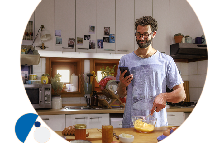 hombre con móvil en una mano y batiendo huevos con la otra