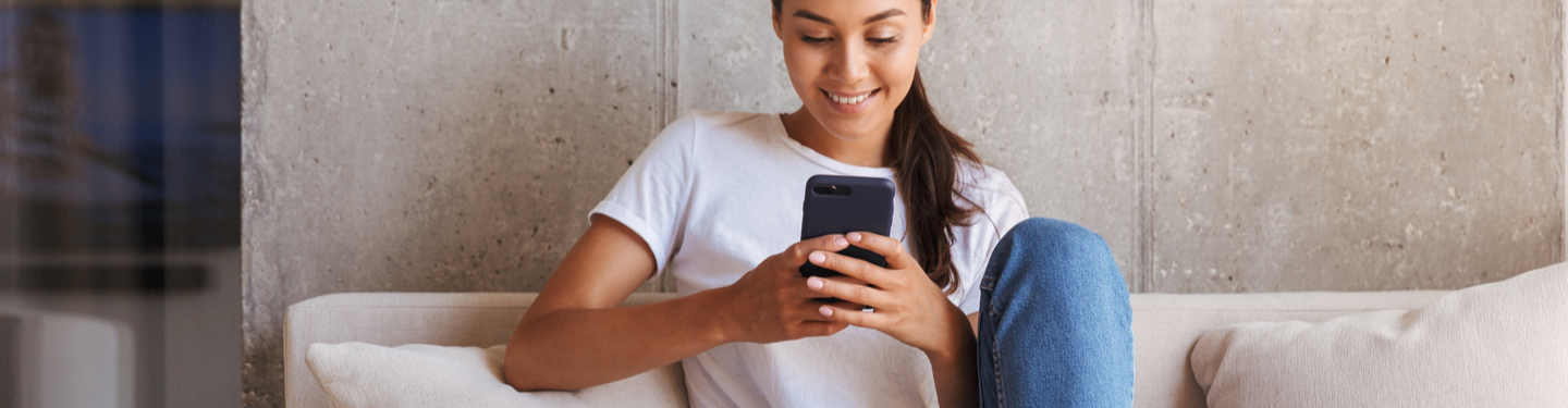 Chica sentada en el sofá utilizando su smartphone