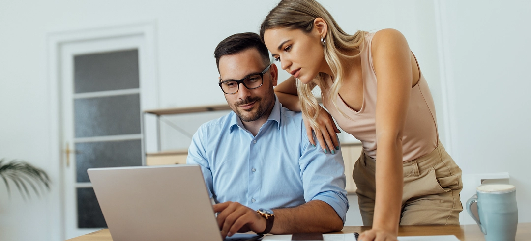Pareja revisando algo en un ordenador portátil desde casa