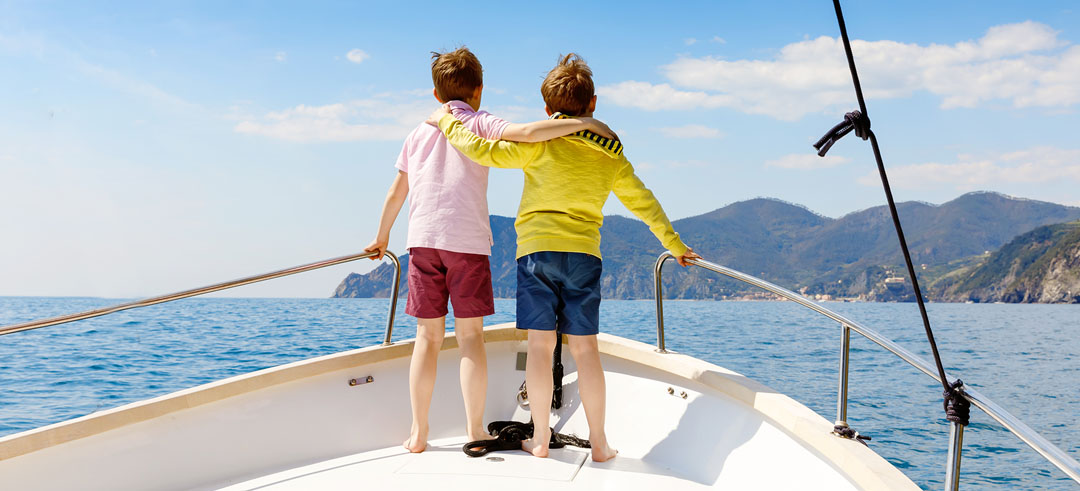 Dos niños agarrados en la proa de un barco mientras navega