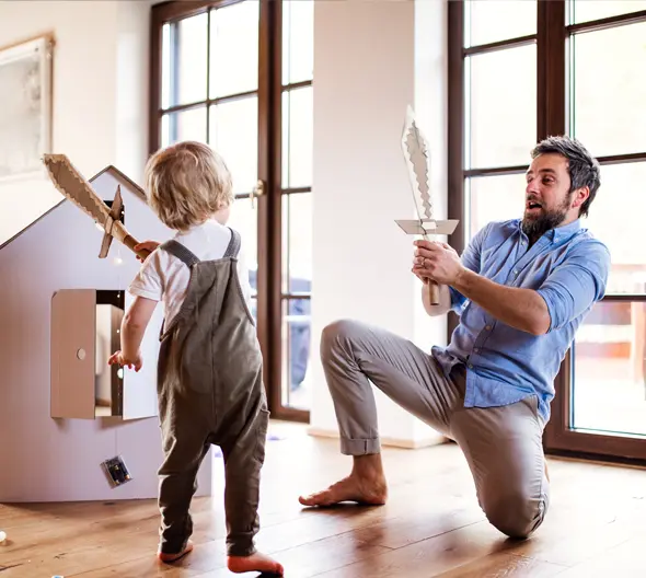 padre jugando con espadas de cartón con su hijo