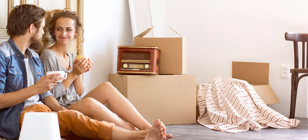 Pareja relajada tomando café y sentada en el suelo con cajas