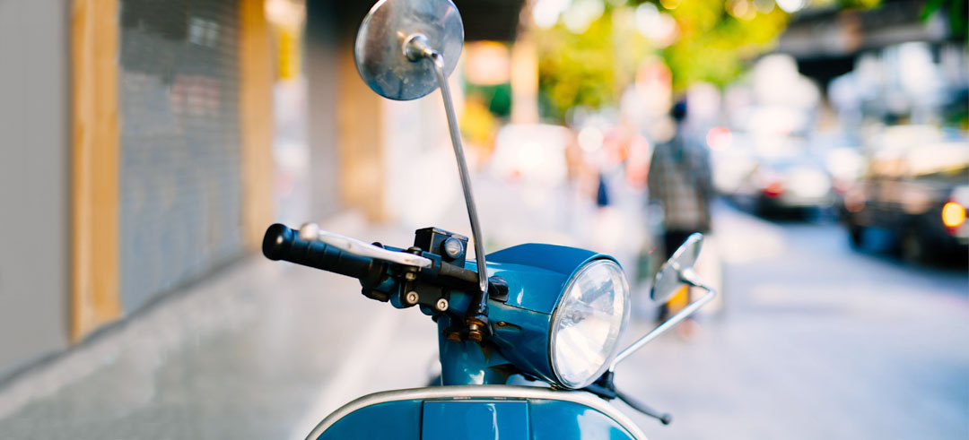 Moto tipo vespa aparcada en la acera