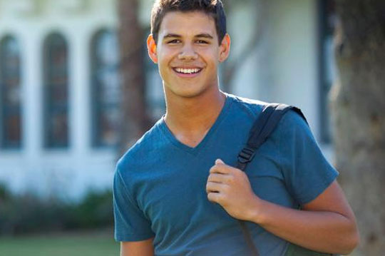 Joven estudiante sonriendo con la mochila sobre un hombro